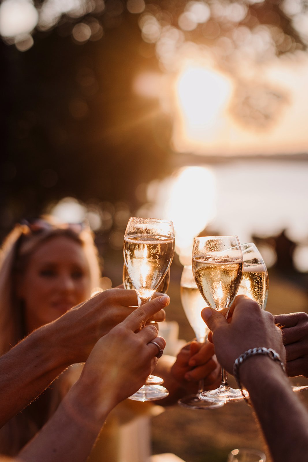 People raising champagne glasses during a sunset toast by the waterfront at Hotel J.